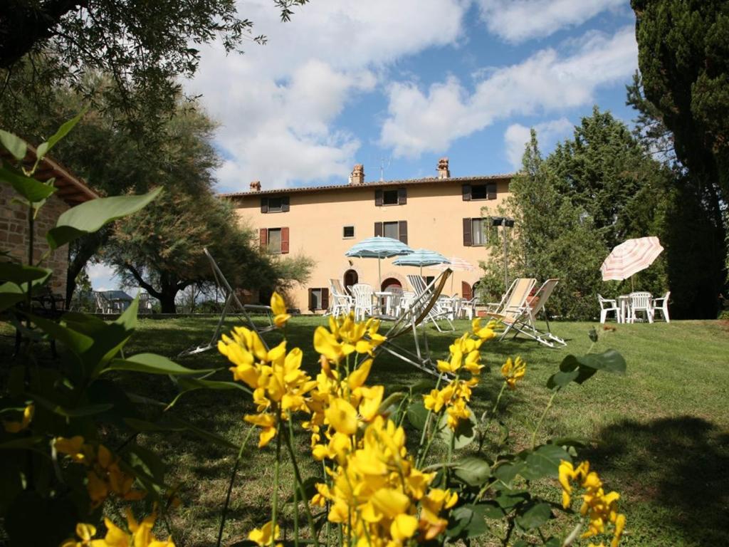 a garden with chairs and umbrellas in front of a building at Agriturismo VILLA MOZART nel verde in Gubbio