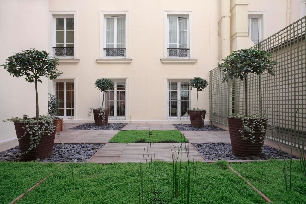 um pátio em frente a um edifício branco com árvores em Hôtel Londres et New York - Teritoria em Paris