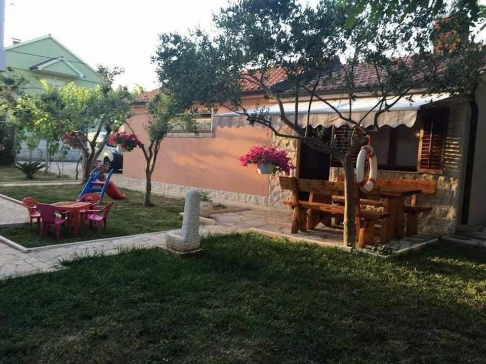 a woman sitting at a table outside of a house at Kata in Privlaka