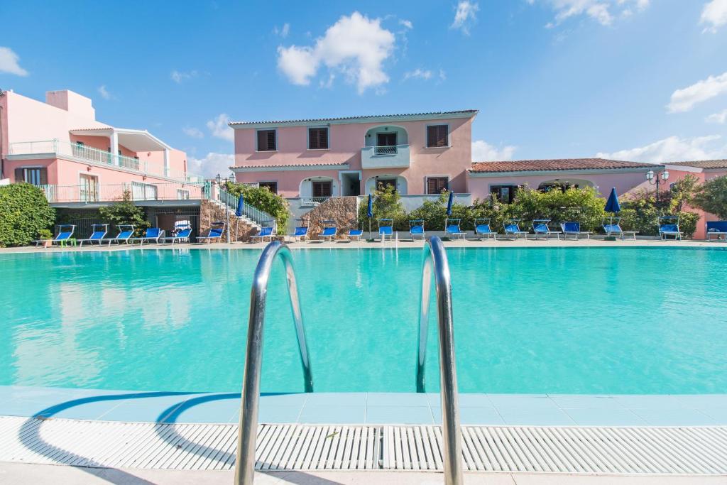 a swimming pool with blue water in a resort at Albergo Residenziale Gli Ontani in Cala Liberotto