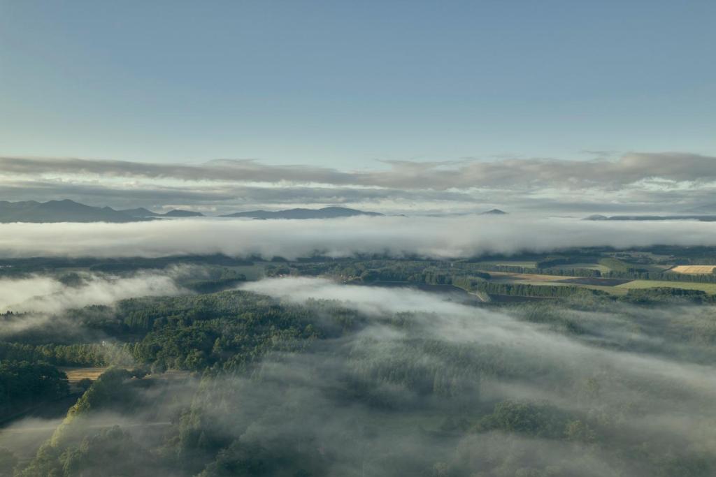an aerial view of a valley of clouds and trees at AZUMA FARM Koiwai in Shizukuishi