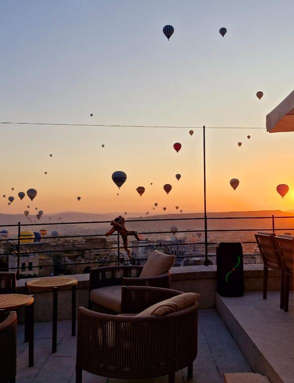 a person standing on a rooftop with balloons in the sky at Cybele in Cappadocia in Uçhisar