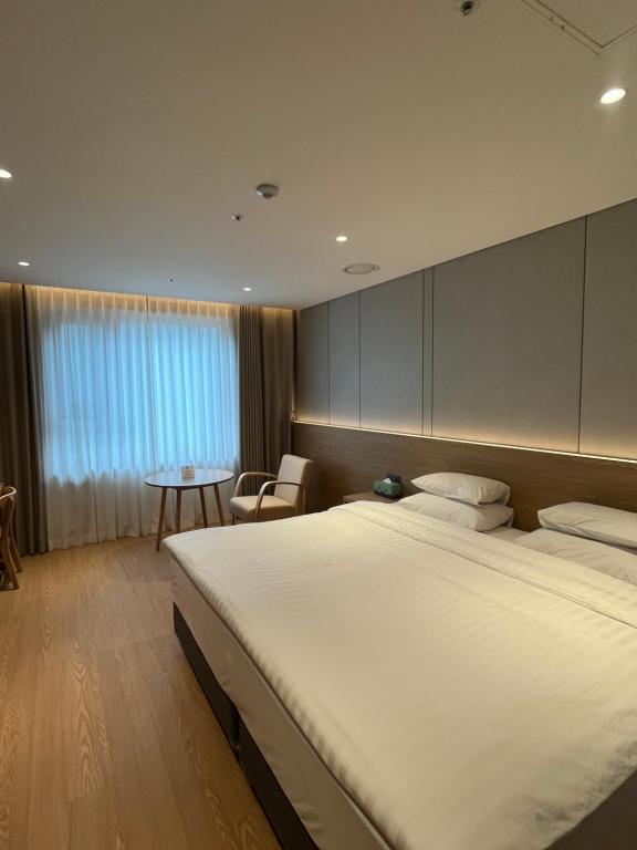 a bedroom with a large bed and a table at Hotel International Changwon in Changwon