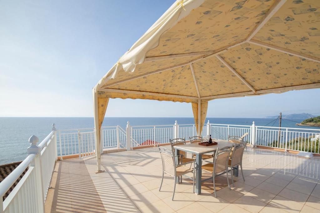 a table and chairs on a deck with the ocean at Seafront Apartment with Panoramic Rooftop Terrace in Paramonas