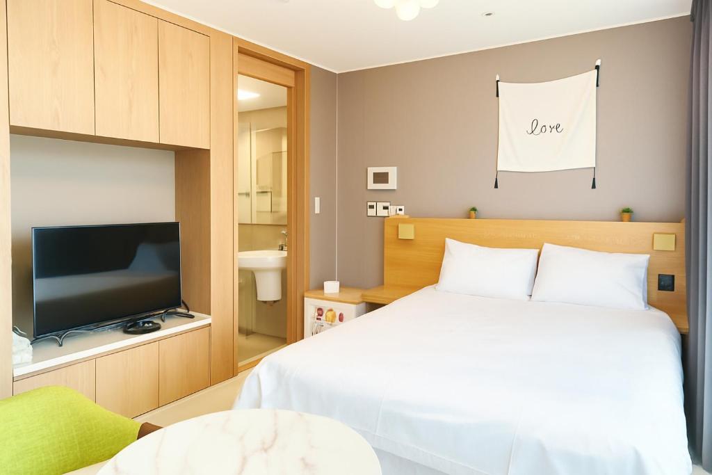 a bedroom with a bed and a flat screen tv at Blue Terra Sokcho in Sokcho