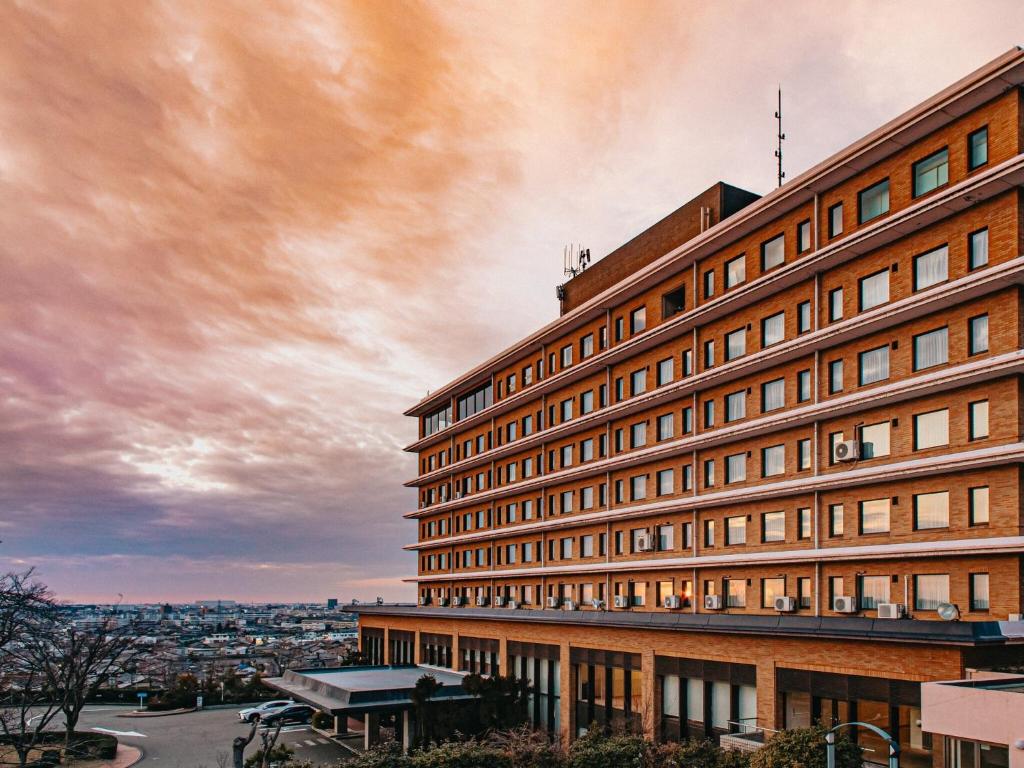 a large brick building with a cloudy sky in the background at Kanazawa Kokusai Hotel in Kanazawa
