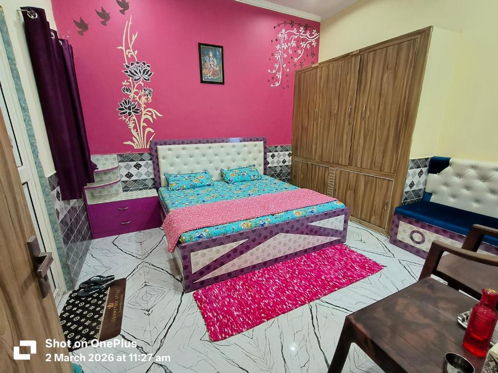 a bedroom with a bed and a pink wall at Vraja Kishori Sewa Dham in Vrindāvan