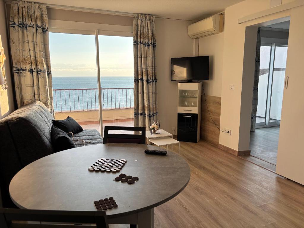 a living room with a table and a view of the ocean at sol appart hotel in Banyuls-sur-Mer