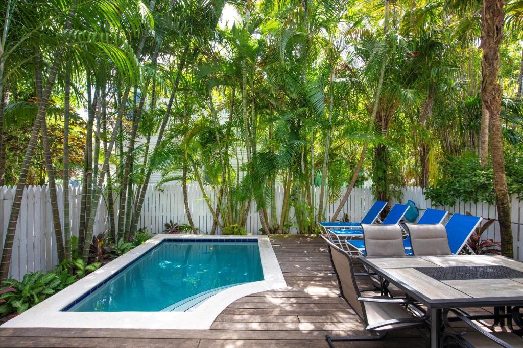 a backyard with a pool and chairs and trees at Palm Royale Windsor Townhomes in Key West