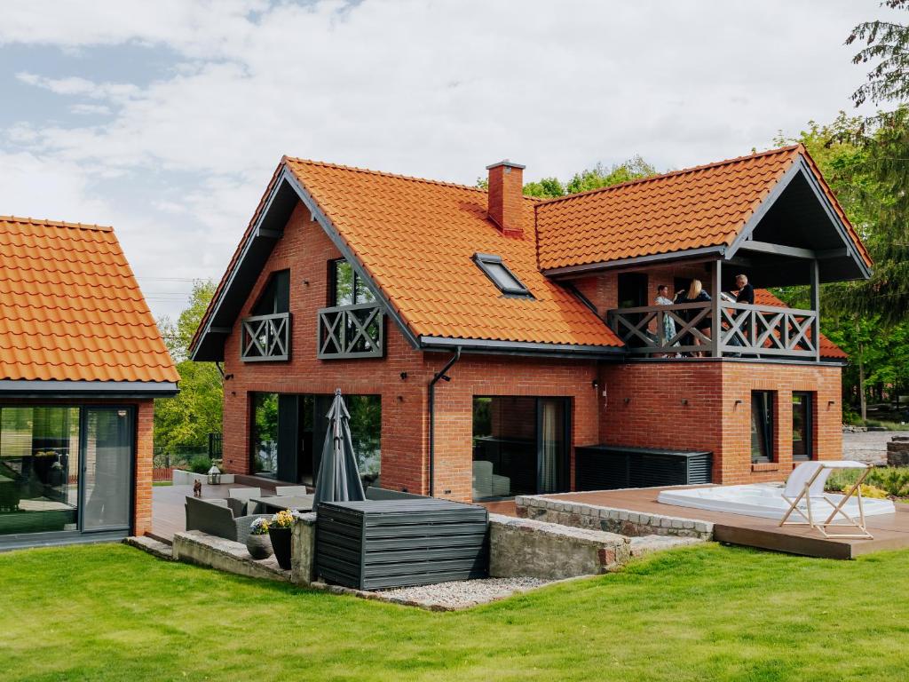 a house with an orange roof with people on the balcony at Villa D'Jora in Mikołajki