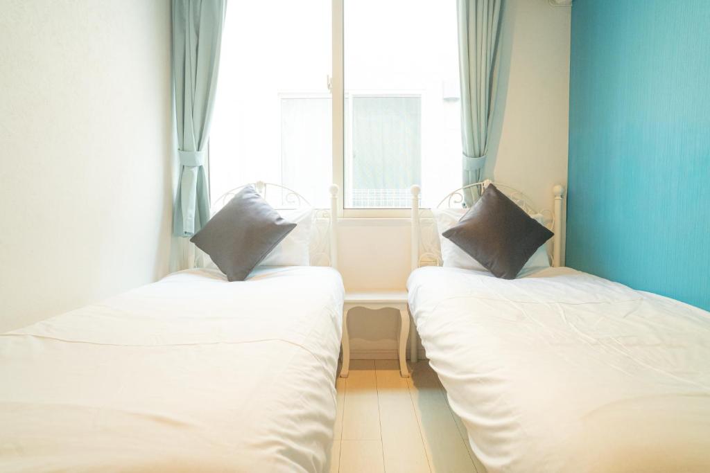 two beds in a room with a window at Pet Friendly 7min to Haneda Quick Access to Shinagawa and Tokyo in Tokyo