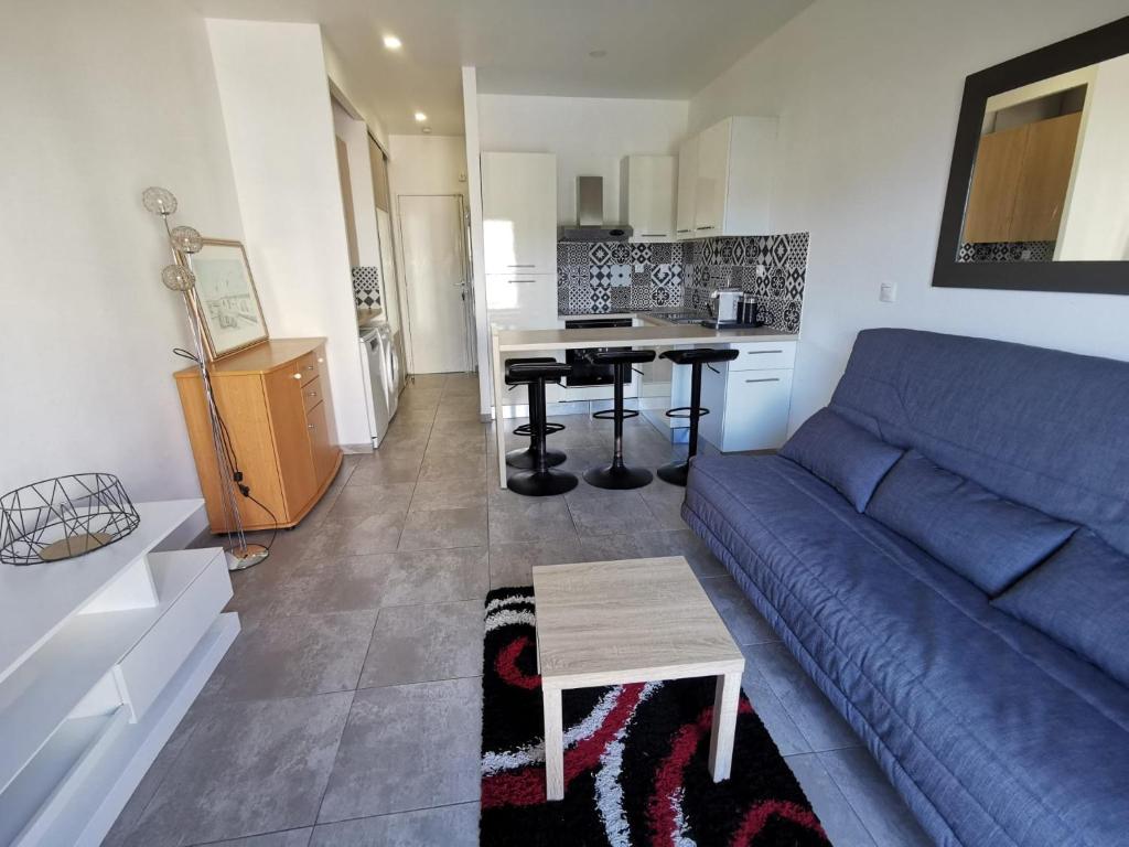a living room with a blue couch and a table at Studio Serenity - Clim - WIFI - Parking - Piscine - Front de mer - Proche commerces et centre ville in Fréjus