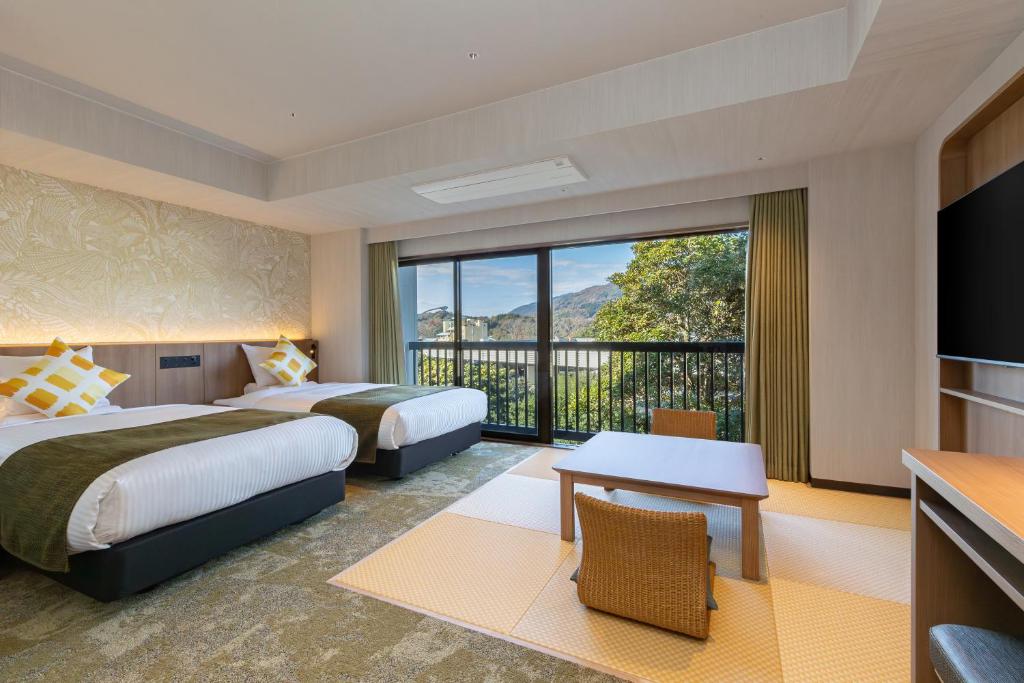 a hotel room with two beds and a balcony at Spa Resort Hawaiians Hotel Hawaiians in Iwaki