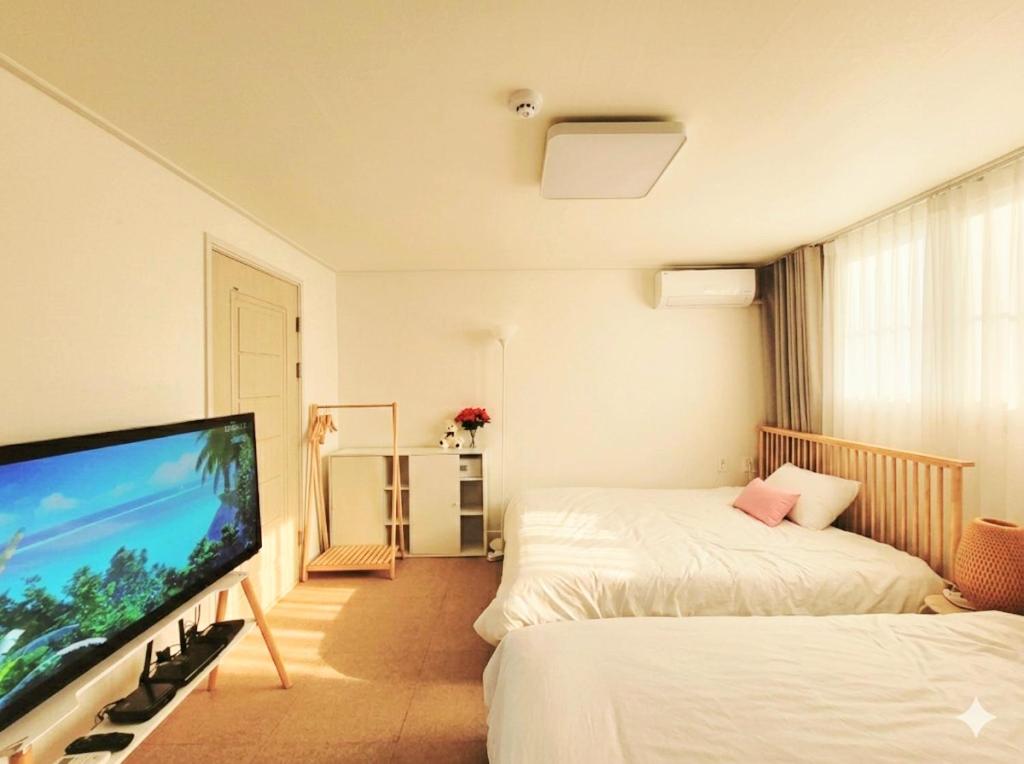 a room with two beds and a flat screen tv at happy stay in Incheon