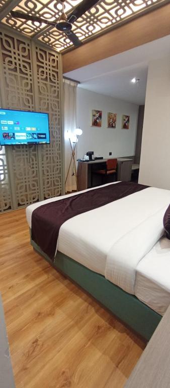 a bedroom with two beds and a desk and a television at AairHotel in Karnal