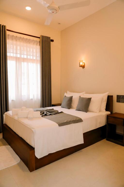 a bedroom with a large white bed with a window at Chamindu Villa Matara in Matara