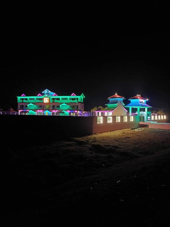 a building with green and blue lights at night at Dev Murti Eco Resort in Chālsa Mahābāri
