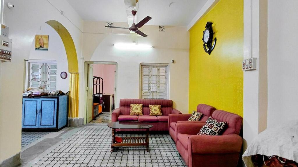 a living room with two couches and a table at Maya's Crest in Howrah