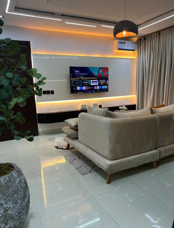a living room with a couch and a tv at TheEliteHavenshortlet in Lekki