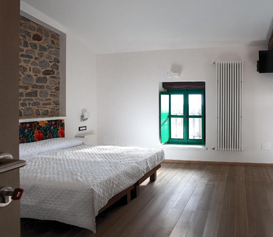 ein weißes Schlafzimmer mit zwei Betten und einem Fenster in der Unterkunft Da Cuful in Reana del Roiale
