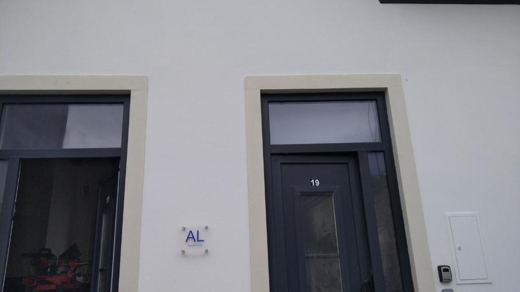 two black doors on a white building with aaa sign at Casas Albano 2 in Caldas da Rainha