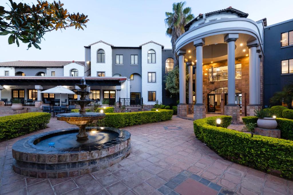 a courtyard with a fountain in front of a building at Basdenwood Hotel in Centurion
