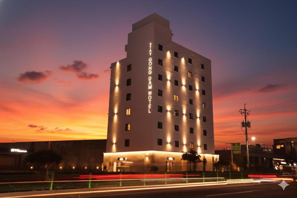 a tall white building with a sunset in the background at 스테이 공담호텔 in Kyū-masan