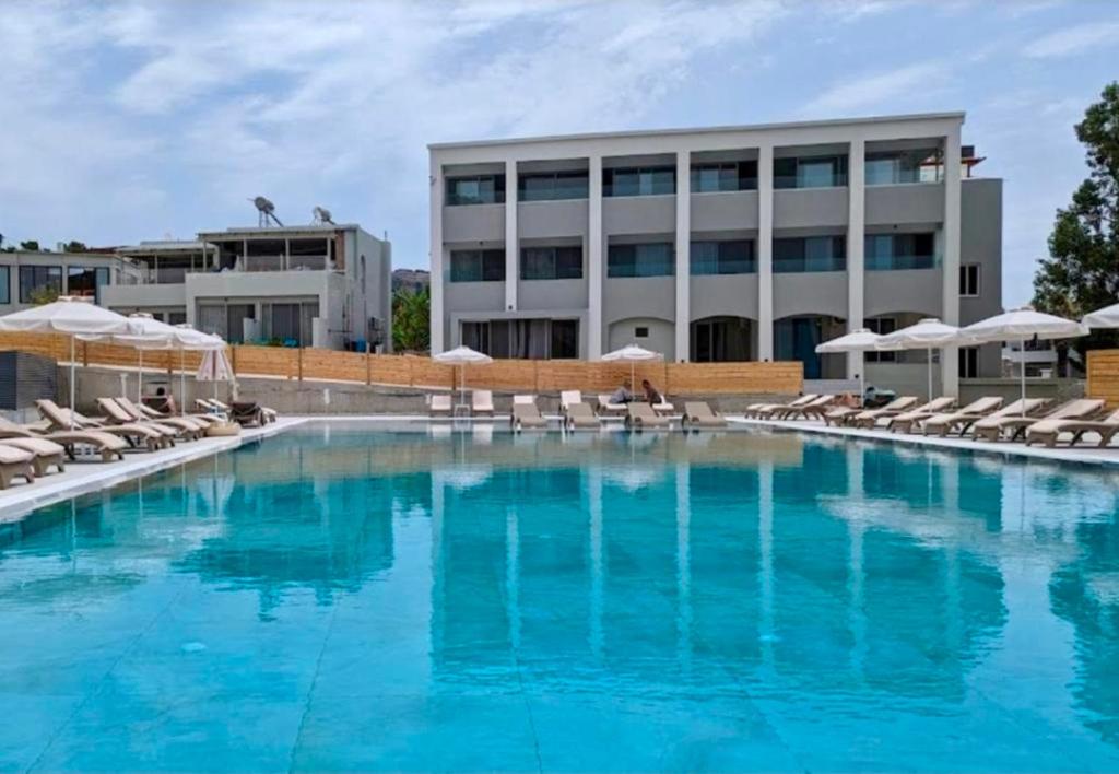 a large swimming pool with chairs and a building at Pals Studios Pefkos in Pefki