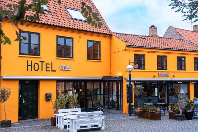 a hotel with two white benches in front of it at Hotel Sniva in Rønne