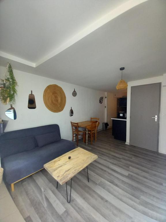 a living room with a blue couch and a table at Le cosy in Clermont-lʼHérault