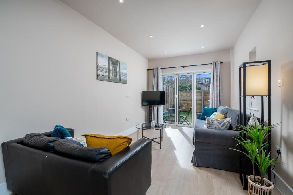 a living room with two leather couches and a television at Exquisite 4Bedroom House 4 Contractors & Large Families with Private Garden, Fully Equipped Kitchen and Close Proximity to Train & Bus Stations in Finchley