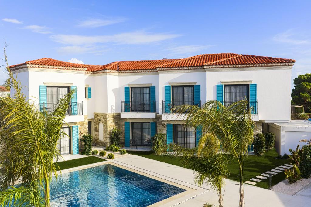 a large white house with a swimming pool and palm trees at Lyse Jülide Hotel in Çeşme