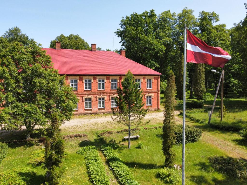 a flag in front of a red brick building at Rozulas skola in Rozula