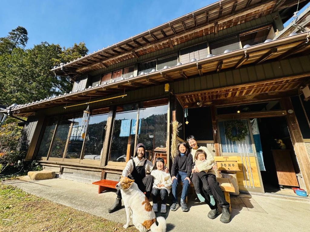 a family posing in front of a house with a dog at Family Homestay Shirokuro Guesthouse in Nakakiri