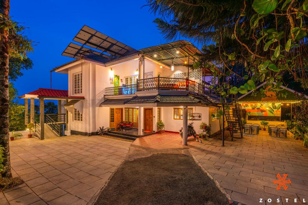 a large white house with a balcony at Zostel Munnar in Devikolam