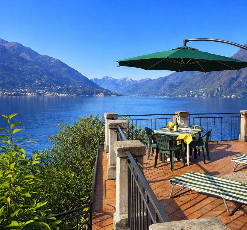 a deck with a table and chairs and an umbrella at Villa crotto Lake View in Perledo