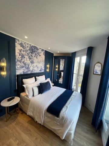 a bedroom with a large bed with blue walls at Hotel Cluny Square in Paris