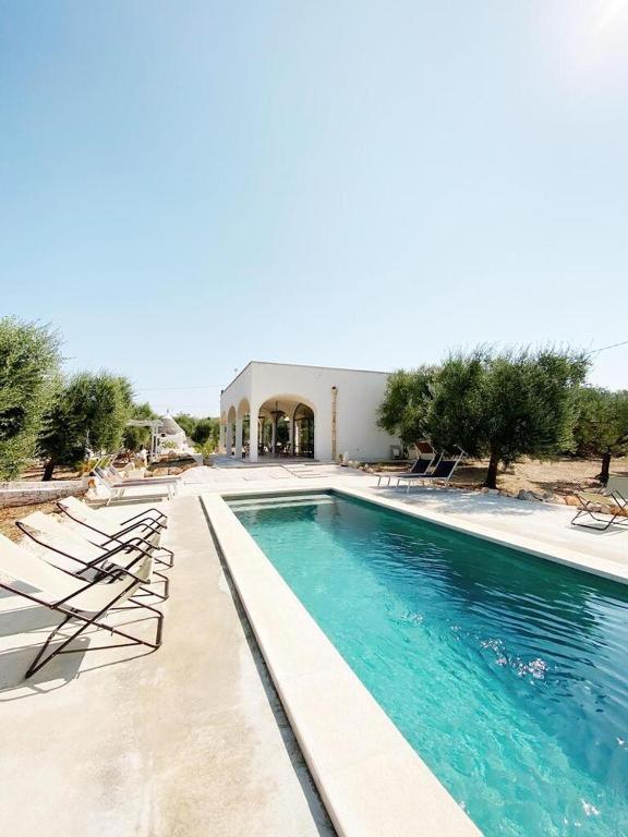 a swimming pool with lounge chairs and a building at Trulli Paradise Ostuni - Villa Privata con Piscina in Ostuni