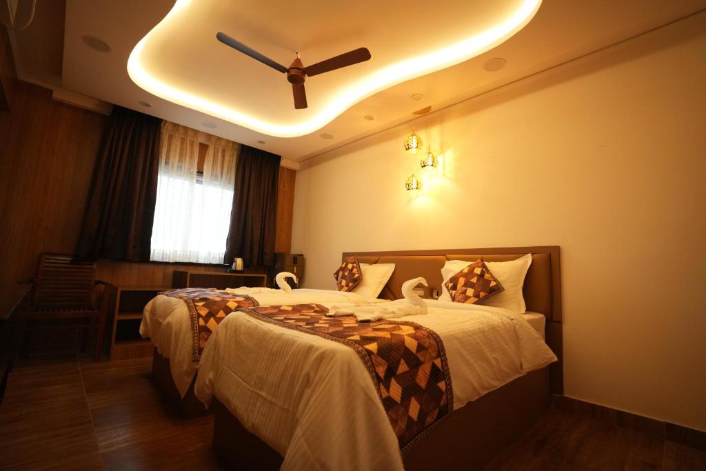 a bedroom with two beds and a ceiling fan at Hotel Alak City in Vallakottai