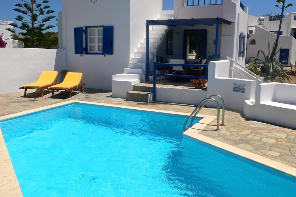 a swimming pool in front of a house at Villa G - Kamari Village in Kastraki
