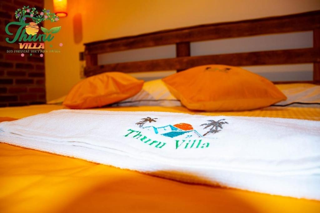 a white towel on a bed with two pillows at Thuru Airport Apartment in Seeduwa