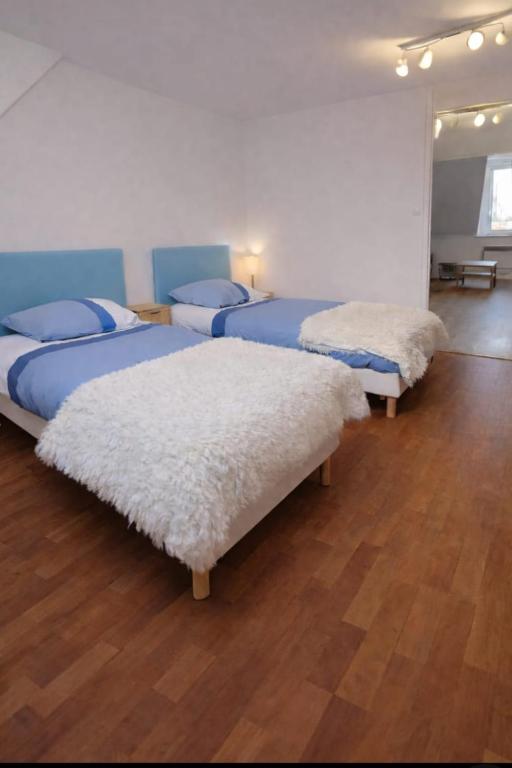 three beds in a room with wooden floors at Functional and convenient apartment avec wifi in La Machine