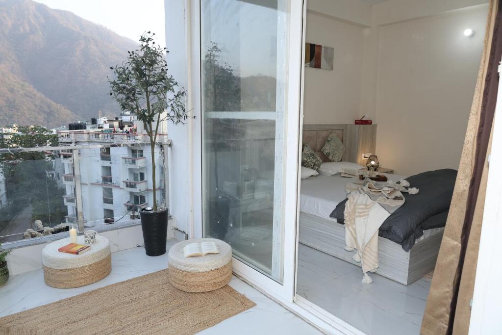 a bedroom with a bed and a balcony with a view at Solskyhaus in Rishīkesh