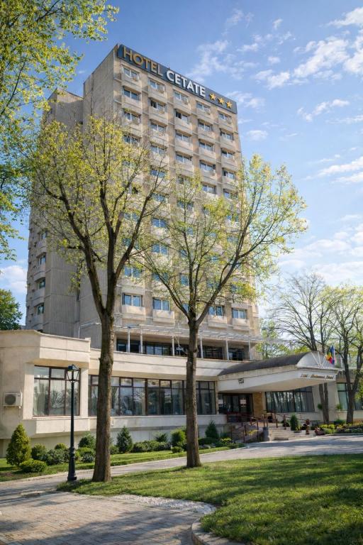 a high gate hotel with trees in front of it at Hotel Cetate in Alba Iulia