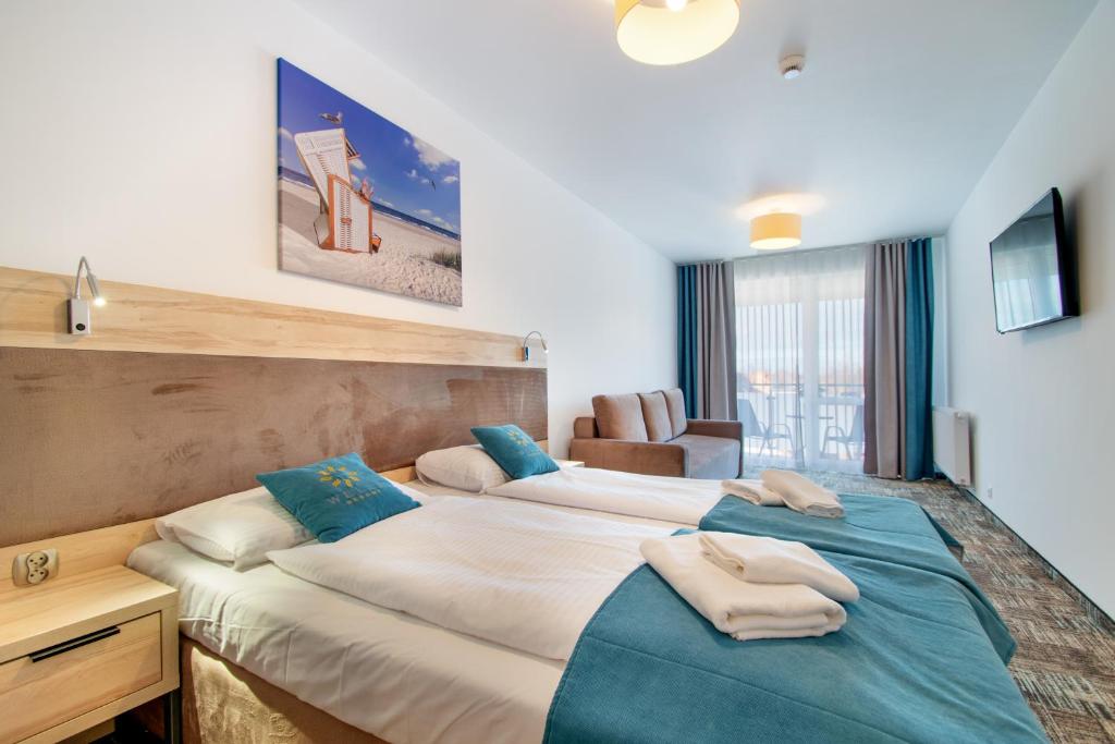 two beds in a hotel room with towels on them at RentPlanet - Welle Resort in Grzybowo