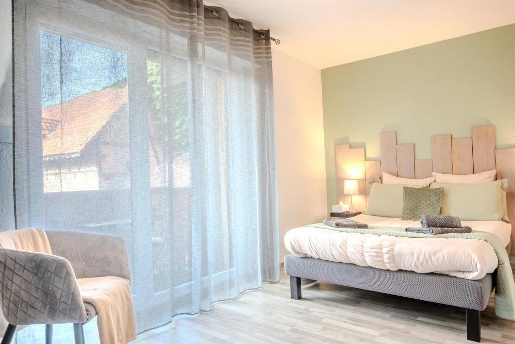 a bedroom with a bed and a large window at Ma Préférence - Studio Cozy - Parking Gratuit - Proche Commerces & Transports in Horbourg