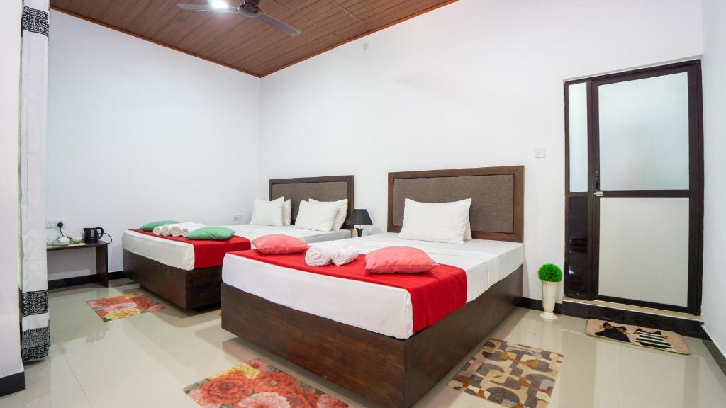 a bedroom with two beds with red and white sheets at Green leaf Villa in Dambulla