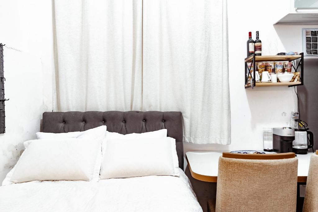 a bedroom with a bed with white pillows and a table at Quartos privativos - São Domingos, Niterói in Niterói