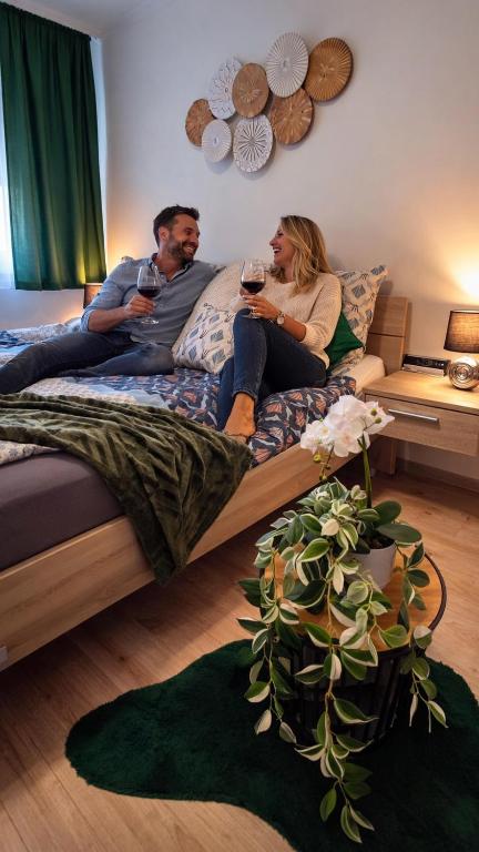 a man and woman sitting on a bed drinking wine at Fehérvár Cappuccino apartman City center, AC, Easy Parking in Székesfehérvár