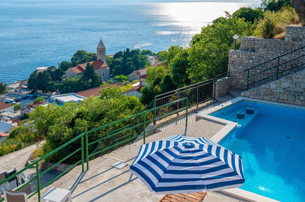a blue and white umbrella sitting next to a swimming pool at Brela Seaview Apartment with Swimming Pool & Parking in Brela